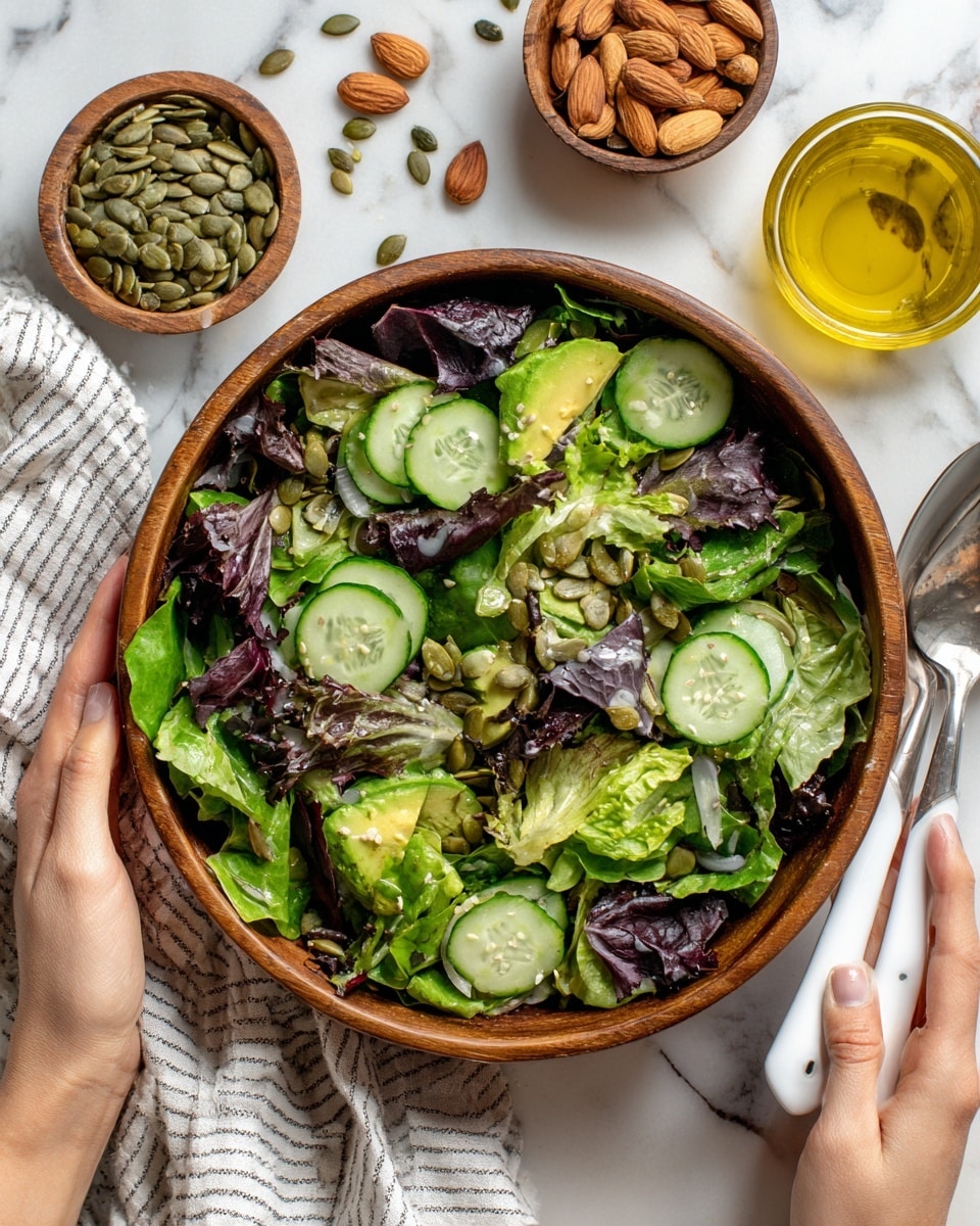 A large wooden bowl filled with a fresh green salad that has several layers: a base of light and dark green leafy lettuce, topped with thin slices of pale green cucumber and light green avocado slices. Scattered on top are dark purple leaves, whole almonds, and some green pumpkin seeds. Two white salad servers are held by a woman's hands, one on each side, mixing the salad. Around the bowl on a white marbled surface with a black and white striped cloth are a small wooden bowl of pumpkin seeds, a cluster of almonds, a small glass bowl of golden olive oil with a spoon inside, and a white plate with small green herb leaves. The lighting is bright and natural. photo taken with an iphone --ar 4:5 --v 7