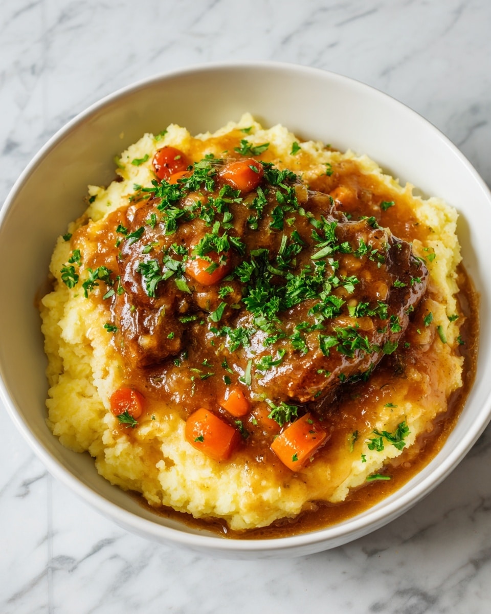 A white bowl holds a round base layer of fluffy, creamy mashed potatoes in a light yellow color with a smooth, slightly textured surface. On top sits a large piece of brown, cooked meat, covered with glossy brown gravy that has chunks of orange carrots and green herbs scattered throughout. Fresh green chopped parsley is sprinkled generously over the meat and gravy, adding a pop of color and texture. The bowl is placed on a surface with white marbled texture, creating a clean and bright look. Photo taken with an iphone --ar 4:5 --v 7