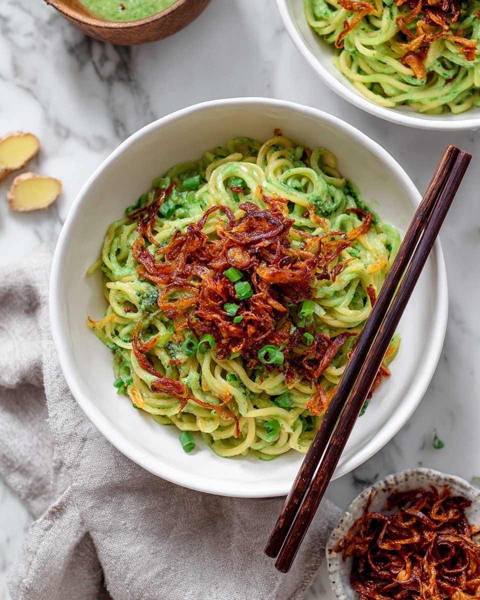 A close-up view of long, thin white noodles covered with a chunky green pesto sauce, lifted by silver tongs. The noodles are tangled together, showing smooth and slightly shiny textures, while the green pesto sauce clings to the strands in uneven patches with visible bits of herbs. The background is a clean, soft white, and the surface beneath is a white marbled texture photo taken with an iphone --ar 4:5 --v 7