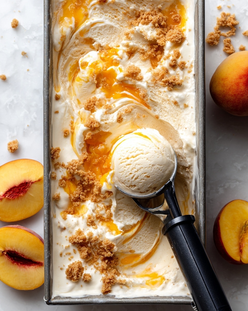 This image shows a silver rectangular metal container filled with creamy light beige ice cream that has swirls and chunks of bright orange fruit mixed in, along with scattered bits of golden-brown crumbly cookie or biscuit pieces. A slightly scooped round ball of the ice cream is held by a dark metallic ice cream scooper placed in the middle of the container. The container is placed on a white marbled surface, with half a fresh yellow-orange peach visible on the right side and a striped cloth and a silver spoon on the left side. The texture of the ice cream looks soft and partially melted. photo taken with an iphone --ar 4:5 --v 7