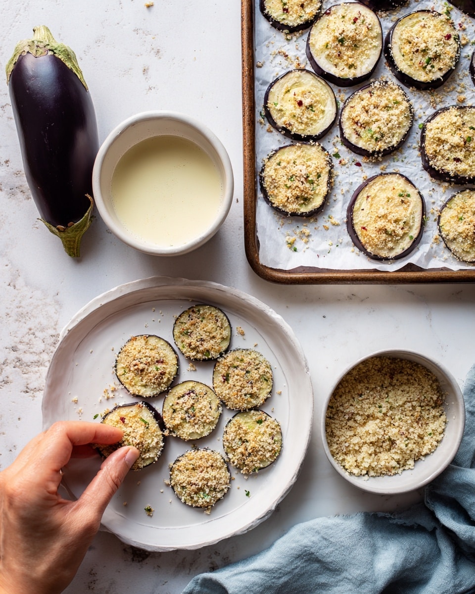 A white plate holds thin round slices of eggplant with purple edges and light cream centers, next to a whole dark purple eggplant on a white marbled surface. There are two white bowls, one with a frothy pale yellow liquid and the other with coarse breadcrumbs mixed with green and red bits. A woman's hand is pressing a round eggplant slice into the breadcrumbs, covering it evenly. A baking sheet with parchment paper shows many breadcrumb-coated eggplant slices lined up neatly. A light blue cloth is beside the bowls. Photo taken with an iphone --ar 4:5 --v 7