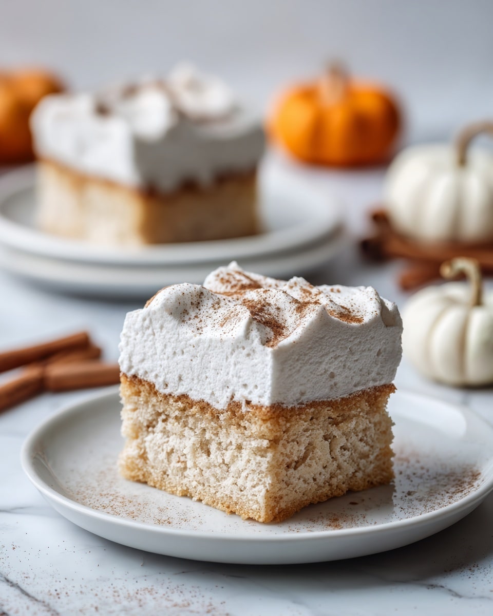 A square piece of cake sits on a white plate with a white marbled surface underneath. The cake has two visible layers: the bottom layer is light brown with a soft, spongy texture, and the top layer is a thick, white cream frosting sprinkled lightly with brown powder, likely cinnamon. In the background, there are more pieces of the same cake on white plates, along with small orange and white pumpkins and cinnamon sticks arranged casually, adding a warm, autumn feel. Photo taken with an iphone --ar 4:5 --v 7