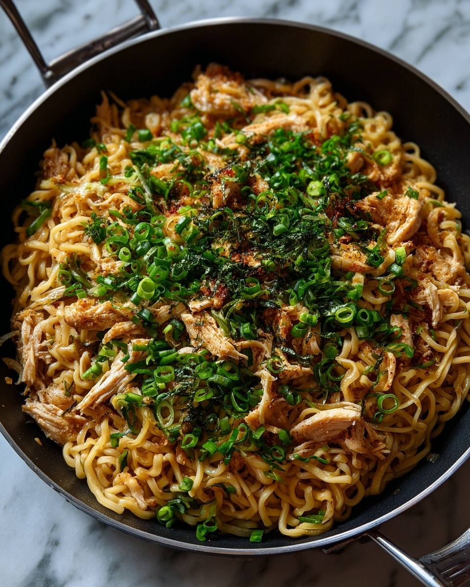 The dish shows a large black pan filled with a mix of thick yellow noodles and shredded light brown chicken pieces, all coated in a slightly glossy sauce giving a warm orange hue. On top and scattered throughout are small pieces of fresh green spring onions adding bright green bursts of color. The noodles and chicken are tangled together evenly, creating a textured look with the smooth noodles intertwined with the fibrous chicken. The pan sits on a white marbled surface, enhancing the colors of the noodles and green onions. photo taken with an iphone --ar 4:5 --v 7
