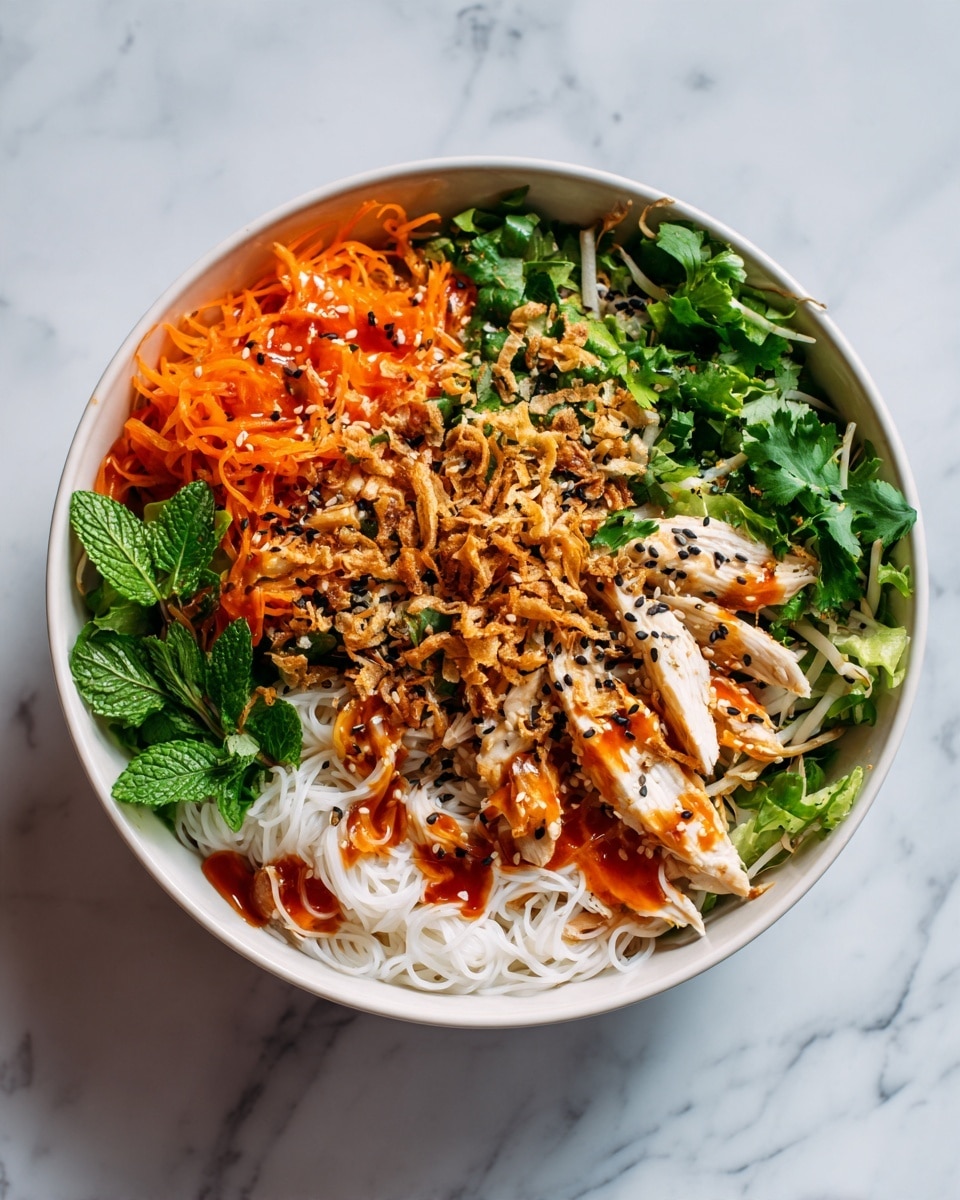 A white bowl is filled with a colorful layered salad. The bottom layer consists of thin white noodles and shredded green lettuce. On top of this lies a mix of fresh green cilantro leaves, thin slices of purple cabbage, and bean sprouts. Next, there are thin orange carrot sticks arranged on one side. Sitting on top are slices of white cooked chicken, drizzled with a light reddish sauce and sprinkled with black sesame seeds. The salad is finished with a sprinkle of crispy fried shallots over the whole dish. The background shows a white marbled surface. Photo taken with an iphone --ar 4:5 --v 7