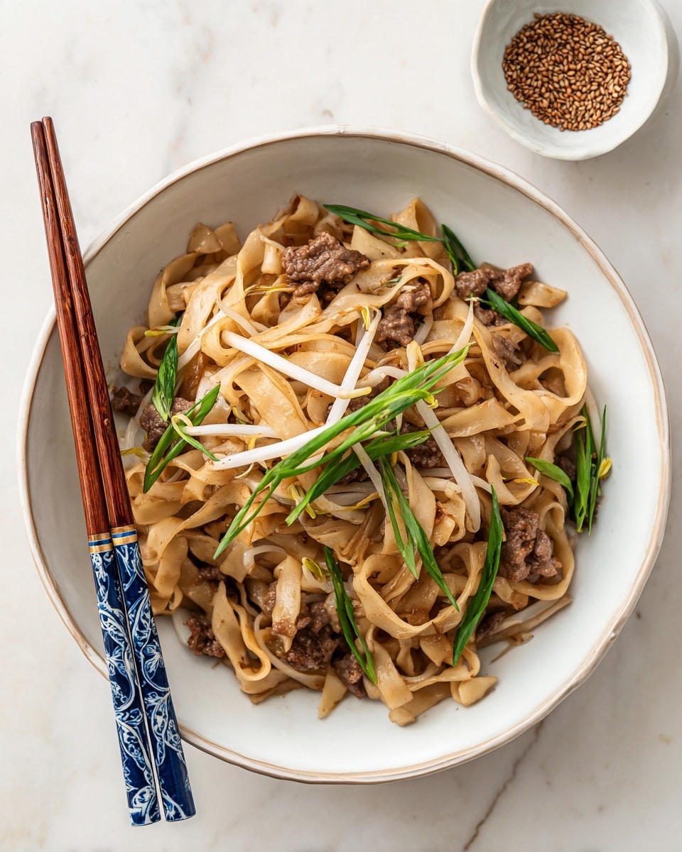A white plate filled with wide flat noodles in a soft brown color mixed with small pieces of dark brown cooked meat and thin bean sprouts of white and light green colors, topped with chopped green onions scattered across. The noodles have a slightly glossy texture, and everything is lightly coated with sauce giving a subtle shine. There are a pair of wooden chopsticks with dark blue and white patterned handles resting diagonally on the plate. In the upper right corner, there is a small white bowl with light brown seeds inside. The plate and bowl sit on a white marbled surface photo taken with an iphone --ar 4:5 --v 7