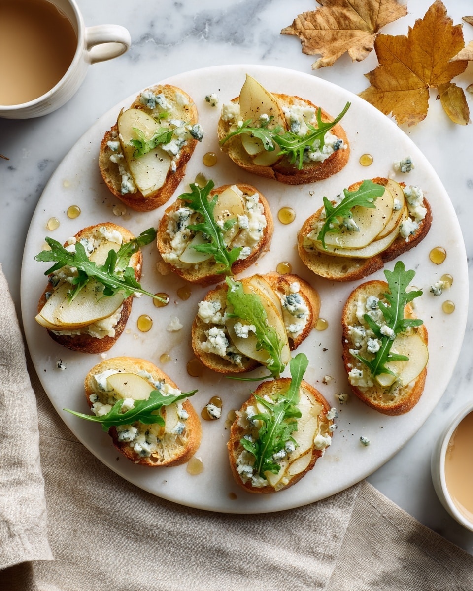 A round white plate with nine small slices of toasted bread, each layered with white creamy cheese spread, two thin yellow pear slices slightly curved, and small chunks of blue cheese. On top of each toast is a small green arugula leaf with a drizzle of golden honey scattered both on the toasts and the plate. The plate is on a white marbled surface with two small white bowls of honey nearby and a few loose arugula leaves and autumn leaves around. photo taken with an iphone --ar 4:5 --v 7