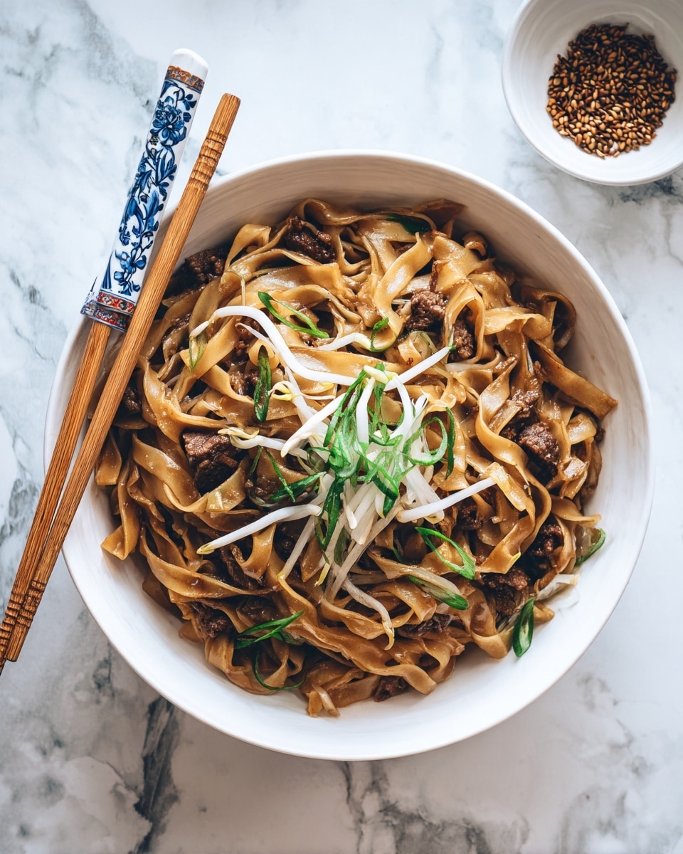 A round white plate filled with wide, flat noodles coated in a dark brown sauce, mixed with pieces of cooked beef that are rich and slightly shiny. Scattered on top are fresh, light green sliced scallions and white bean sprouts with a crisp texture, adding freshness to the dish. Wooden chopsticks with intricate blue and white patterns rest on the left side of the plate. In the top right corner, a small white bowl with some brown seeds is visible on a white marbled surface. The whole image has a clean, bright look with a soft natural light. photo taken with an iphone --ar 4:5 --v 7