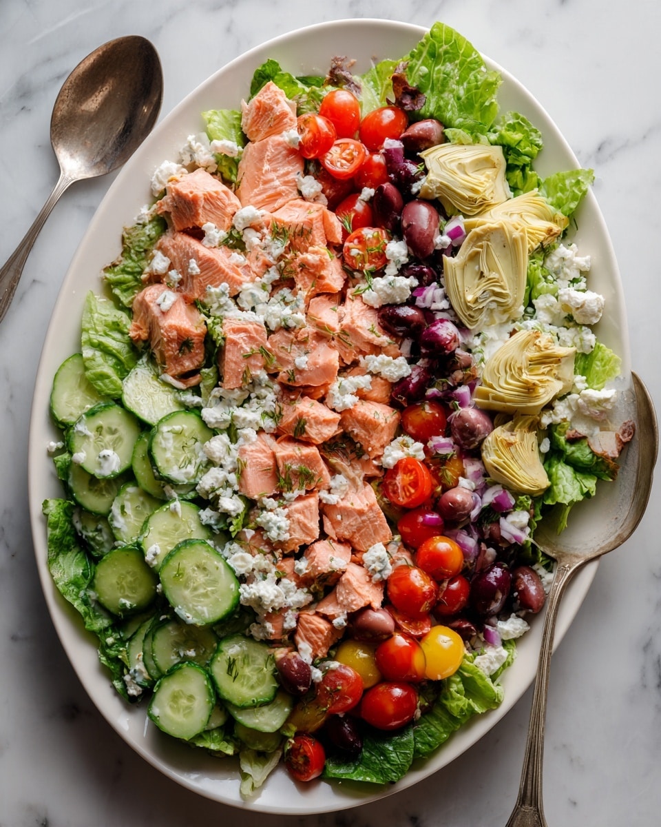 A white oval plate is filled with a colorful salad layered in sections. The bottom layer is fresh green lettuce leaves. On top of that are slices of pale pink salmon placed in the center. Around the salmon, there are thick slices of light green cucumber and quartered bright red cherry tomatoes. Scattered throughout are soft cream-colored artichoke hearts and dark purple olives. Crumbled white feta cheese is sprinkled generously over the whole salad, with a little black pepper on top. A silver serving spoon is placed on the right side of the plate, resting on the white marbled surface photo taken with an iphone --ar 4:5 --v 7