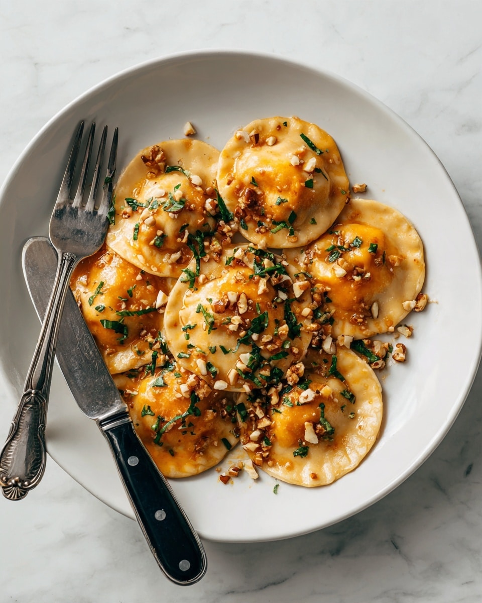 There are six round ravioli pieces on a white plate with a white marbled texture surface beneath. Each ravioli is light beige with a slightly browned edge, and two are cut open showing a bright orange filling inside. The ravioli are covered in a light brown sauce with small chunks of pecans scattered on top and around them. A fork and knife with black handles rest on the edge of the plate. photo taken with an iphone --ar 4:5 --v 7