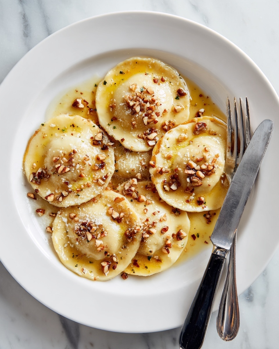 A white plate holds six browned ravioli pieces, each with a wrinkled edge and a slightly glossy surface from a light sauce. Two ravioli in the front are sliced open, revealing a bright orange filling inside. The dish is topped with small chopped nuts scattered around and over the ravioli, and a thin layer of brown sauce with oily spots lightly coats the plate underneath. A fork and knife with black handles rest behind the ravioli on the plate, which is set on a white marbled surface. Photo taken with an iphone --ar 4:5 --v 7
